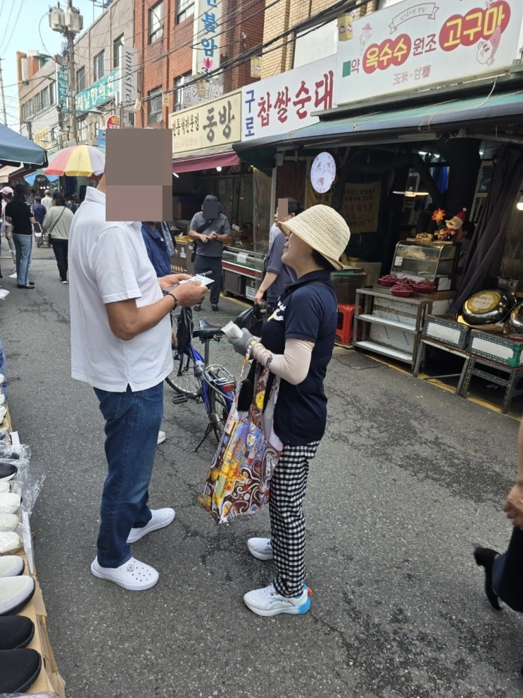 전통시장에서 주민에게 병원 판촉물을 직접 전달하며 인사하는 모습